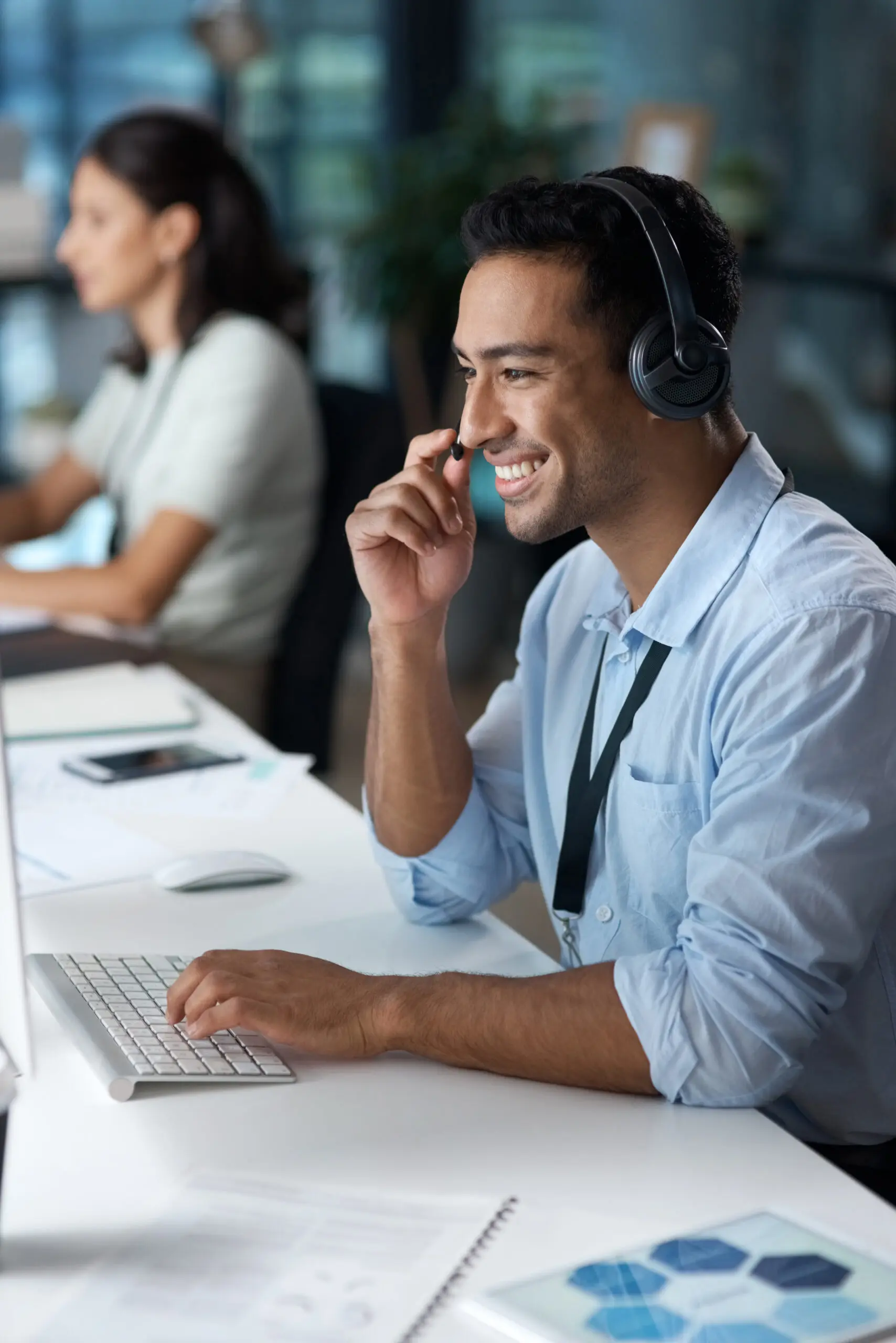 Smiling male BPO agent with headset actively working at a computer, demonstrating professional and friendly customer support.