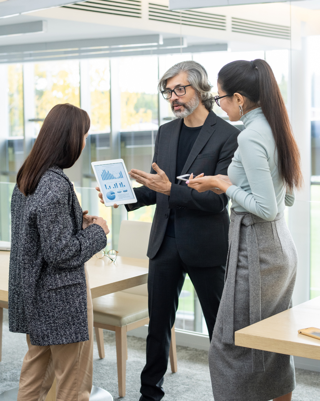 Expert-Consultation-Strategic-Planning-for-Ecommerce-Management Three professionals discussing financial charts on a tablet, showcasing expert consultation for ecommerce management services and strategic planning.